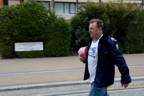 A police officer wearing a police jacket thrown over jeans and a t-shirt, walking down Worcester Boulevard shortly after the 22 February 2011 earthquake.