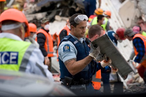 Emergency personnel lifting a metal beam from the ruins of the Canterbury Television Building on Madras Street during their search for trapped people.