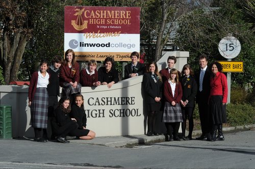 Students from both Cashmere High School and Linwood College gathered around the entrance gate of Cashmere High School. Behind them is a sign that reads "Cashmere High School welcomes Linwood College." The sign has both of their logos on it.